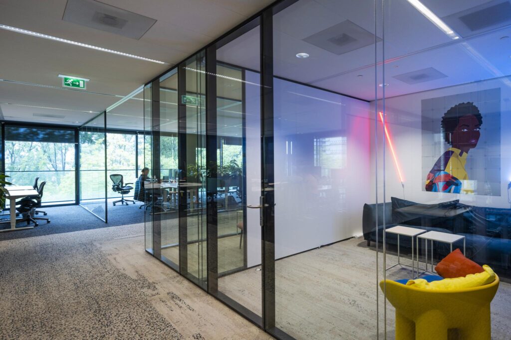 Modern office space on Gustav Mahlerlaan with glass meeting rooms, colorful furniture, and contemporary artwork.